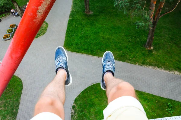 Feet Hanging in the Air First Person View. Above the City Park. Riding a Ferris Wheel Top View