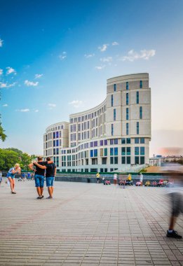 Minsk, Beyaz Rusya - 16 Ağustos 2017:-Merkezi çocuk Gorki Parkı Minsk'te. Bir kız alır resimleri, iki erkek olan Posing onun için. Yeni Modern görünümünü bağımsızlık Caddesi üzerinde binası inşa. Uzun pozlama bulanıklık hareket manzara modunda