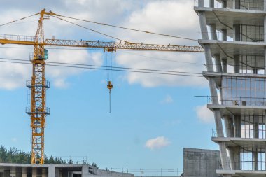 İnşaat alanında, yüksek katlı bir bina betonarme bulutlu gökyüzü karşı yapılmış bitmemiş iskelet ile vinç ile