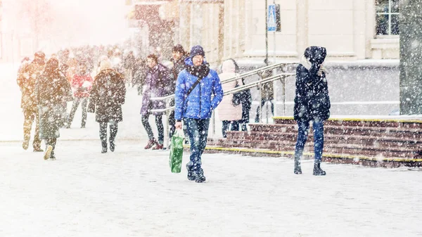 En man i blå jacka går i snöfall — Stockfoto