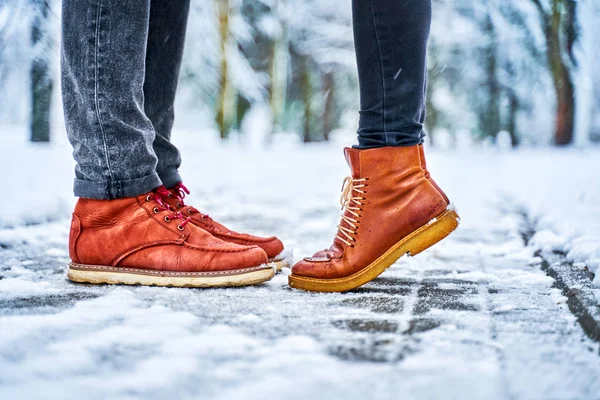 Ноги пары на снежном тротуаре в коричневых сапогах — стоковое фото