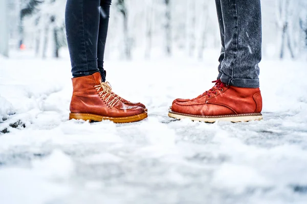 Feet of a couple on a snowy sidewalk in brown boots — Stock Photo, Image