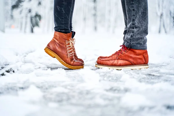 Feet of a couple on a snowy sidewalk in brown boots — Stock Photo, Image