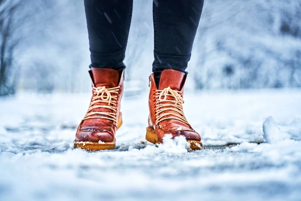 Voeten van een vrouw op een besneeuwde stoep in bruine laarzen — Stockfoto