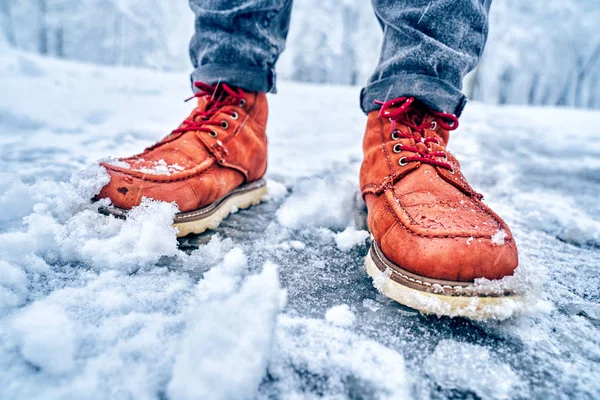 Voeten van een man op een besneeuwde stoep in bruine laarzen — Stockfoto