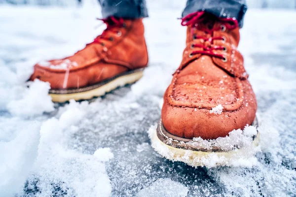Ноги человека на снежном тротуаре в коричневых сапогах — стоковое фото