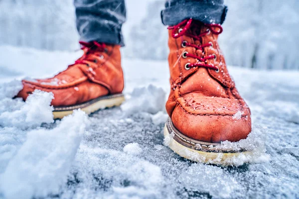 Fötter av en man på en snöig trottoar i bruna stövlar — Stockfoto