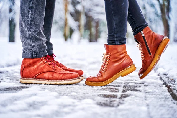 Egy pár lába egy havas járdán barna csizmában. Stock Kép