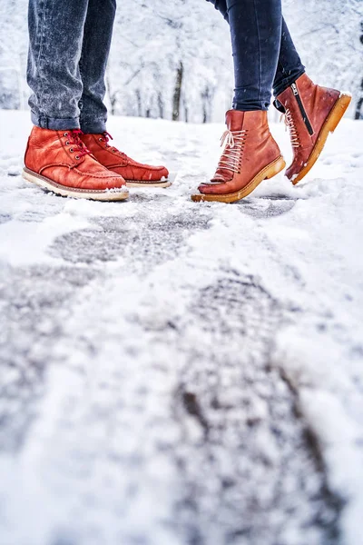 Pieds d'un couple sur un trottoir enneigé en bottes brunes Images De Stock Libres De Droits