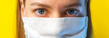 Sarı arka planda gazlı bez maskeli bir kadının portresi kameraya bakıyor. Kendi sağlığınızı viral enfeksiyondan korumak için. Coronavirus konsepti.
