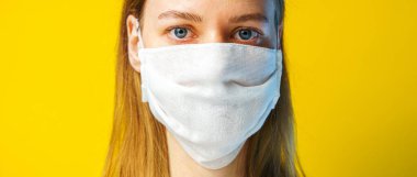 Sarı arka planda gazlı bez maskeli bir kadının portresi kameraya bakıyor. Kendi sağlığınızı viral enfeksiyondan korumak için. Coronavirus konsepti.