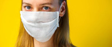 Sarı arka planda gazlı bez maskeli bir kadın portresi ve fotokopi alanı kameraya bakıyor. Kendi sağlığınızı viral enfeksiyondan korumak için. Coronavirus konsepti.