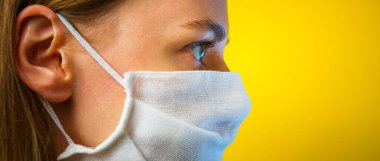 Sarı arka planda gazlı bez maskeli bir kadının portresi. Kendi sağlığınızı viral enfeksiyondan korumak için. Coronavirus konsepti.