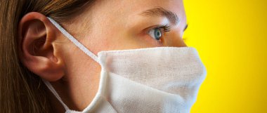 Sarı arka planda gazlı bez maskeli bir kadının portresi. Kendi sağlığınızı viral enfeksiyondan korumak için. Coronavirus konsepti.