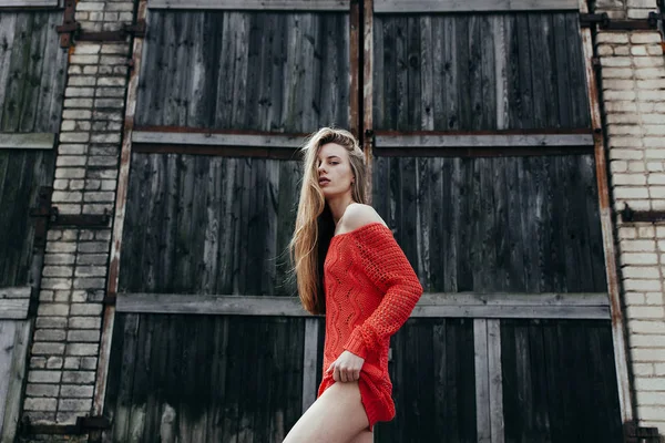 Das sexy Mädchen im roten Pullover über einer Wand — Stockfoto