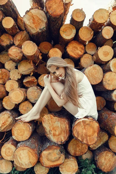 Natural girl in dress sitting on logs — Stock Photo, Image