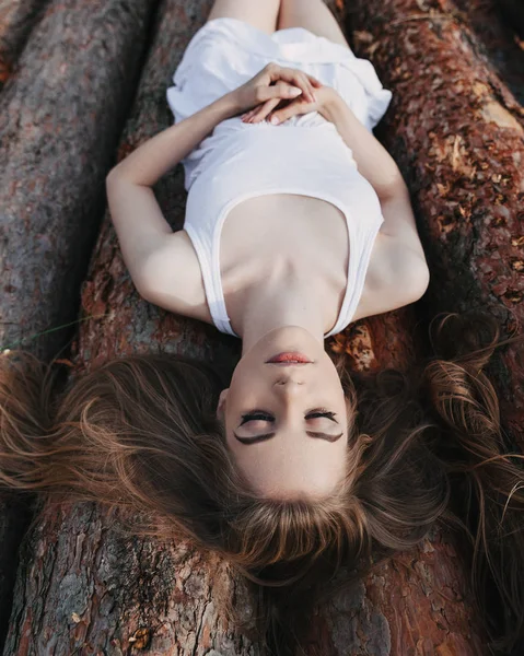 Girl with closed eyes lies on logs — Stock Photo, Image