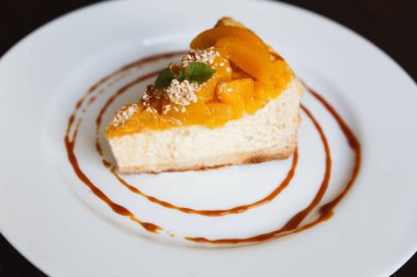 Karamel ve peaches beyaz bir plaka üzerinde Cheesecake