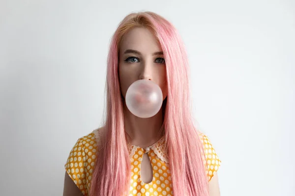 The girl with the pink hair is blowing bubble gum — Stock Photo, Image
