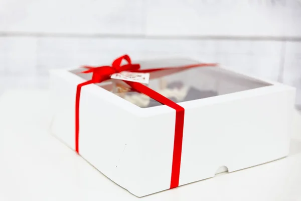 Cupcakes in a white box with a red ribbon on a white background