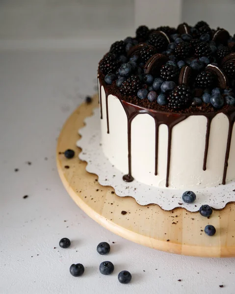Fehér torta csokoládéval és friss bogyókkal egy fehér hátterű fa tálcán — Stock Fotó