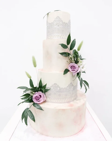 Pastel de boda con flores moradas y hojas verdes con fondo blanco — Foto de Stock
