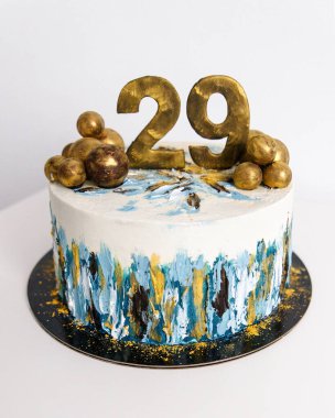 Beyaz doğum günü pastası mavi ve altın renkli çikolata toplarıyla süslenmiş.