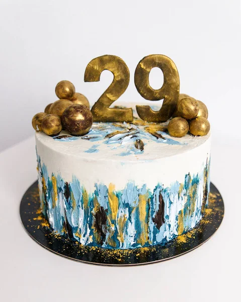 Vit födelsedagstårta är dekorerad i blått och guld med bollar av choklad — Stockfoto