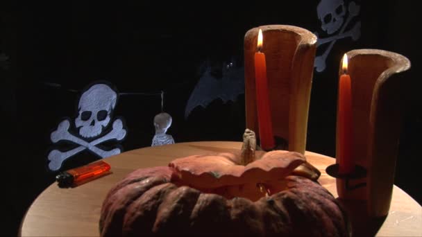 На фоне Хэллоуина подают стол с тыквой и горящими свечами — стоковое видео