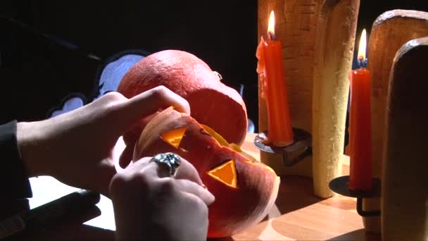 吸血鬼的獠牙牙齿放在万圣节南瓜口中，点着蜡烛的表 — 图库视频影像