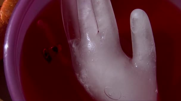 Stroboskoplichter auf Eis in Handform in rotem Cocktail, gruseliger Totenkopfring — Stockvideo