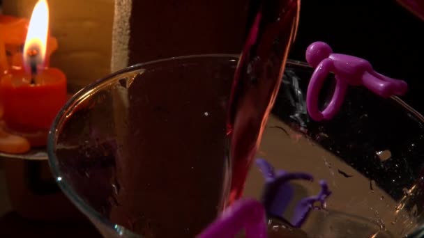 Verser une boisson rouge dans le verre, flamme de bougie sur le fond, gros plan 