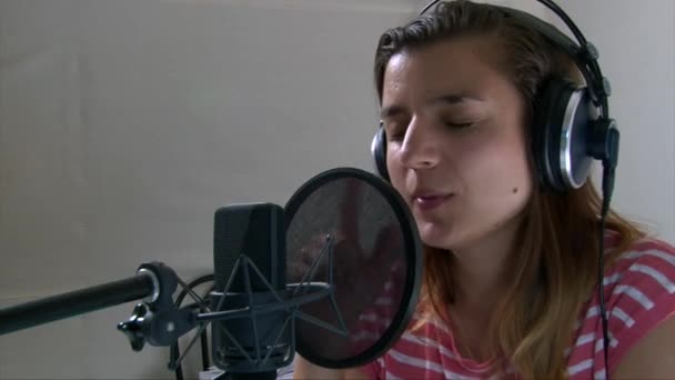 Девушка эмоционально поет хард-рок песню в студийном микрофоне — стоковое видео