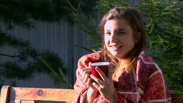 Junges Mädchen in warmes Plaid gehüllt und trinkt heißen Tee — Stockvideo