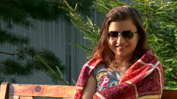 Gros plan portrait de fille souriante dans des lunettes de soleil enveloppé dans un plaid chaud — Video