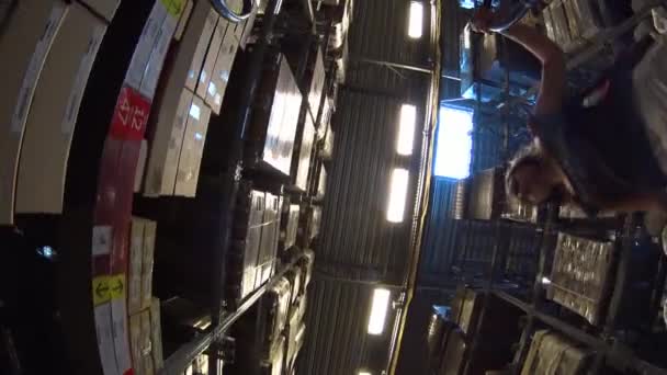 POV flickan flytta åka kundvagn genom möbler lagerställe, sätta lådan på vagn, underifrån — Stockvideo