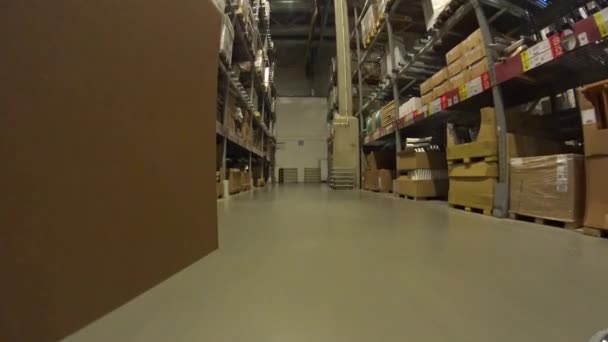 POV Shopping cart with large cardboard box moving  between the rows of shelves through furniture store and turning back — ストック動画