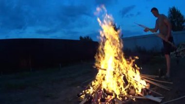 Uzun boylu adam yakacak odun sopa açık ateş koydun.