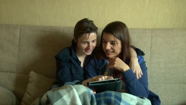 Ragazze lesbiche che usano tablet, baci, sorridenti e ridenti sul divano — Video Stock