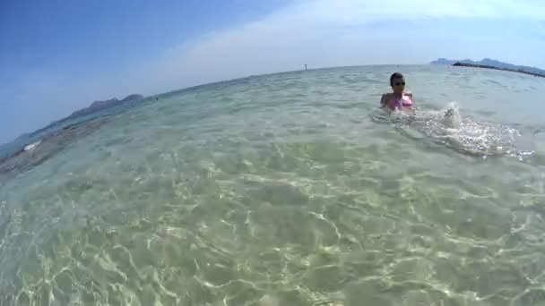 Giovane bella donna in occhiali da sole galleggiante in mare cristallino sulla sua soleggiata vacanza estiva su un'isola tropicale, guarda sulle gambe — Video Stock