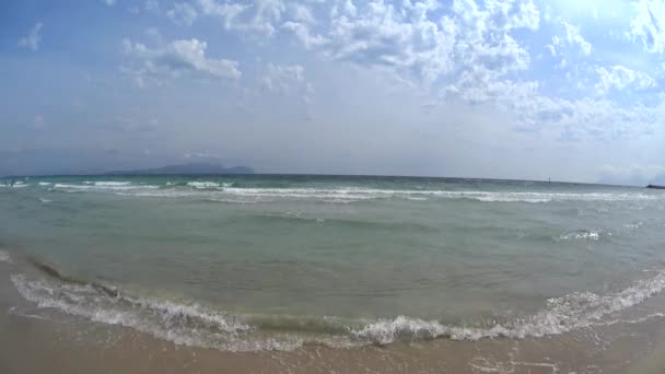 Menina na praia andando em camiseta branca e biquíni rosa salpicando no mar águas rasas do oceano, dia ensolarado, água azul clara, Maiorca, Espanha — Vídeo de Stock