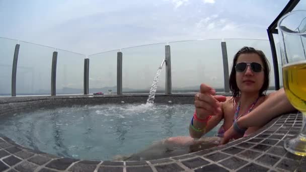 Frau entspannen am Rande des Whirlpools im Resort. junge Frau beobachtet schöne Landschaft und trinkt Cocktail-Bier. sie genießt ihren Urlaub im Resort im Luxushotel — Stockvideo