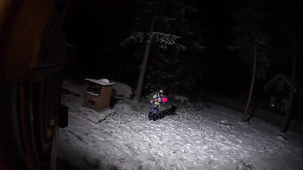 Kid flicka gör snö ängel på bakgården på natten — Stockvideo