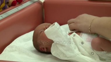 Yeni doğan bebek tulum giymiş bir hastane hemşire koyar