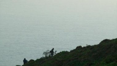 Turist adam ve bir fotoğrafçı bir dağ cliff okyanus kıyısında,