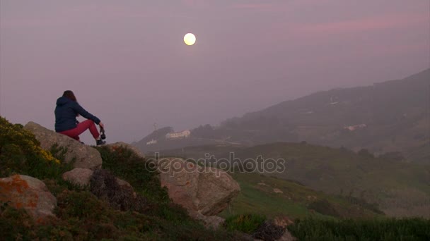 Ragazza seduta su una roccia di montagna con una bottiglia di vino — Video Stock