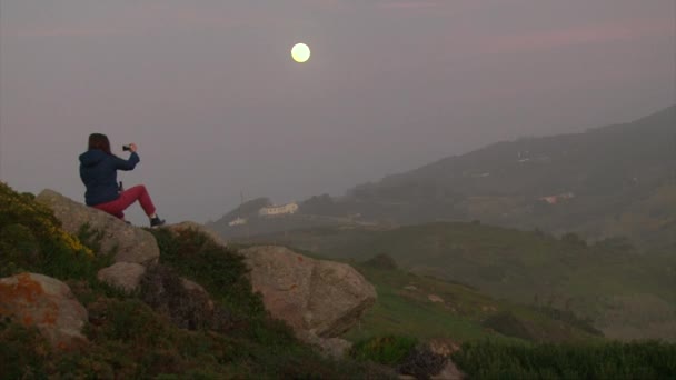 Ragazza scattare foto selfie su smartphone, mentre seduto su una collina rocciosa — Video Stock