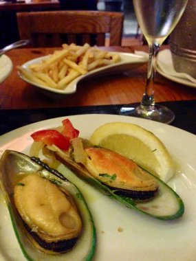 Midye ve limon tabak, bardak beyaz şarap ve patates kızartması, Restoran tablo üzerinde