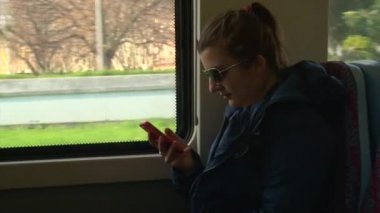 Tren veya otobüs üzerinde oturan smartphone kullanarak güneş gözlüğü güzel kız