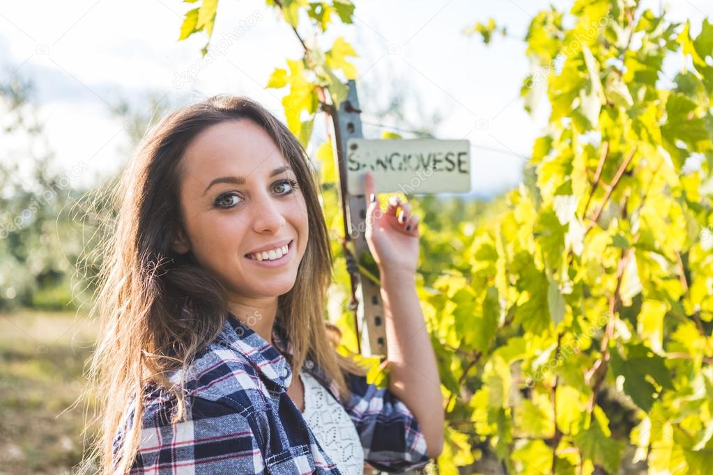 Girl pointing on Sangiovese sign in vineyard 